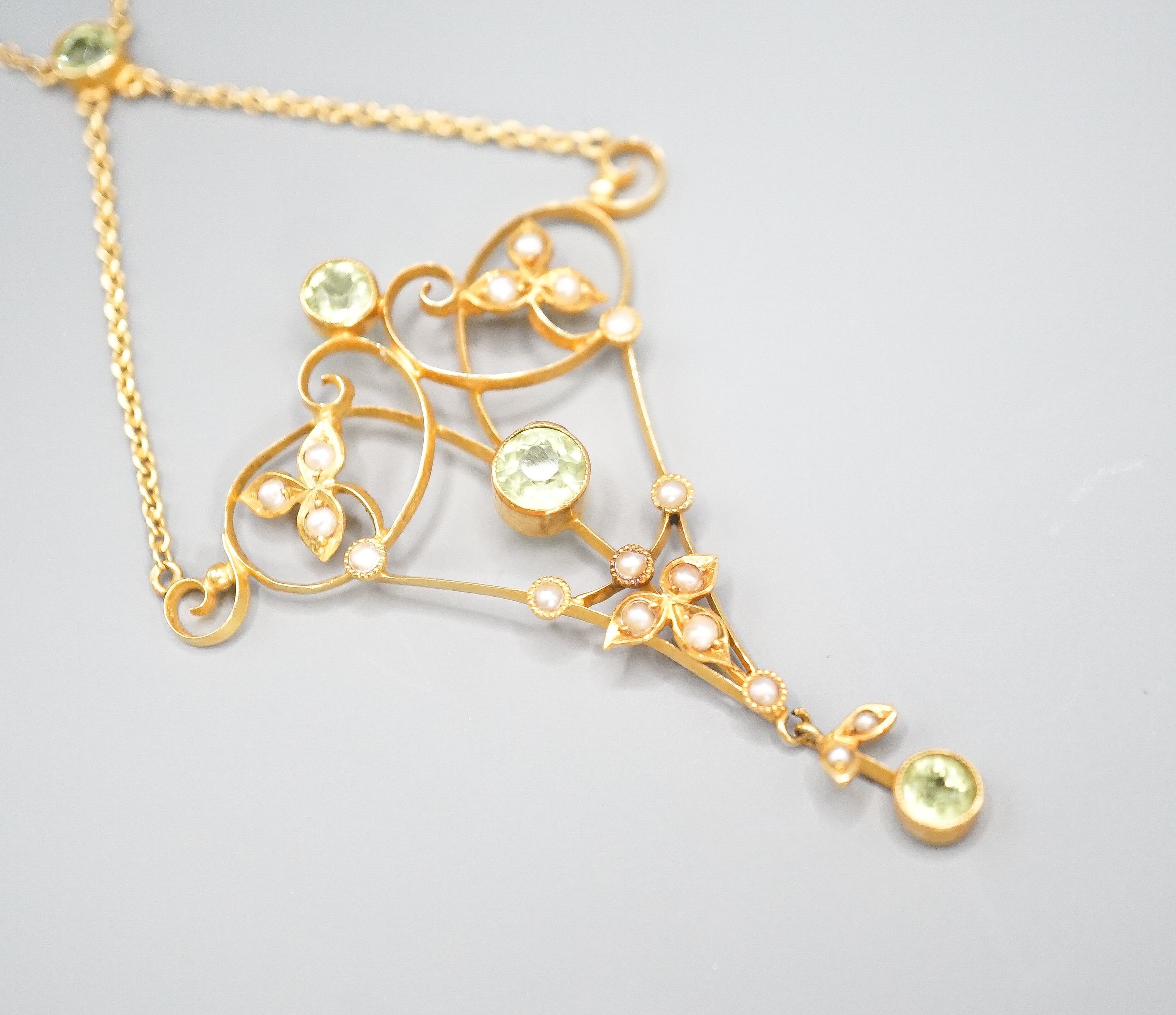 An Edwardian 9c yellow metal peridot seed pearl set pendant necklace, approx. 52cm overall, gross weight 4.4 grams.